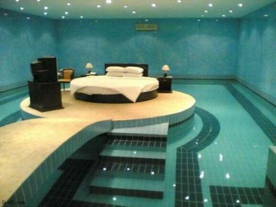 Chambre au milieu d'une piscine qui entoure la plateforme où est posé le lit